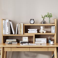 a wooden desk topped with books and a teddy bear next to a shelf filled with books