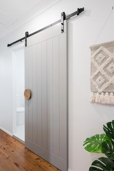 an open sliding door in a white room with wood flooring and potted plant