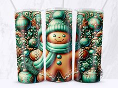 three tumblers decorated with christmas decorations and a snowman on the front one has a green scarf around his neck