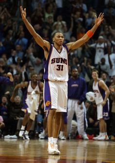 a basketball player holding his arms up in the air while standing on top of a court