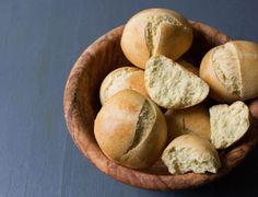 a wooden bowl filled with rolls on top of a table