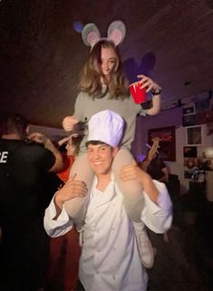 a woman is holding onto a man wearing mouse ears and an apron while they are dancing