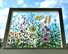 a painting on the side of a building that has flowers painted on it and blue sky in the background