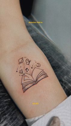 a woman's arm with an open book tattoo on it