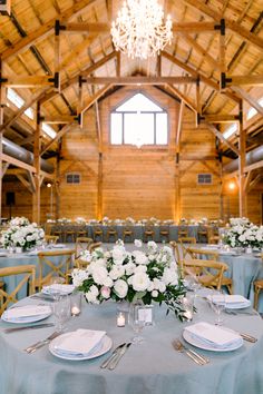 the tables are set with white flowers and place settings in front of a chandelier