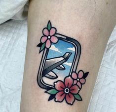 an airplane with flowers on the side of its leg is seen in this tattoo design