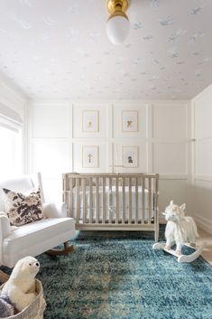 a baby's room with a crib, rocking chair and stuffed animals on the floor