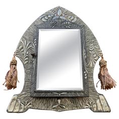 an ornate mirror with tassels on the sides and a square shaped mirror above it