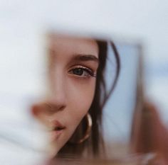 a close up of a woman's face looking at her reflection in a mirror