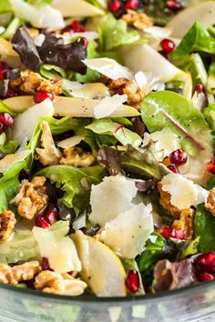 a salad with spinach, cheese and pomegranates in a glass bowl