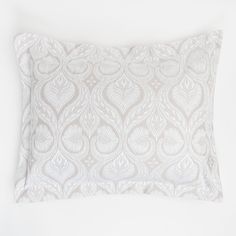 a white pillow with an intricate design on the front and back, against a white background