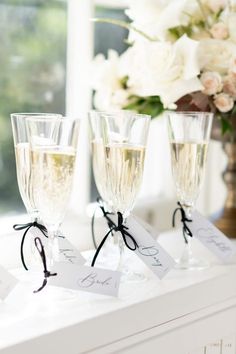 three wine glasses are sitting on a table with place cards in front of the glasses