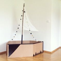 a cardboard boat sitting on top of a wooden floor