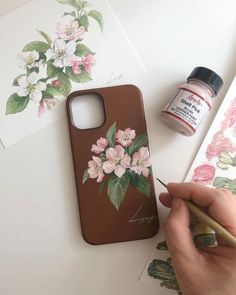 someone is drawing flowers on the back of their phone case with a pencil and watercolor