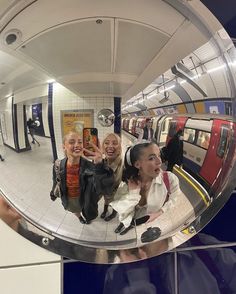 two women taking a selfie in a mirror at a subway station with their cell phone