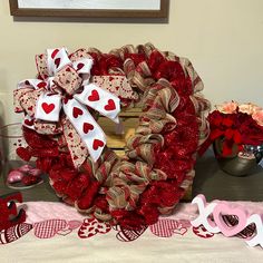 a valentine's day heart shaped wreath sitting on top of a table next to other decorations