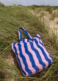 The oversized, multi-use Wave Tote is stylish enough to compliment any outfit and sturdy enough to carry your laptop, farmer's market finds, or beachside essentials. Crafted from 100% cotton canvas and hand block printed in bright pink and ocean blue by artisans in India, every tote is unique. Blue Canvas Bag For The Beach, Pink Canvas Beach Bag For Summer, Summer Pink Canvas Beach Bag, Summer Pink Cotton Beach Bag, Pink Summer Cotton Beach Bag, Pink Cotton Summer Beach Bag, Pink Cotton Bag For Summer, Pink Cotton Bags For Summer, Pink Canvas Beach Bag