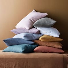 a pile of pillows sitting on top of a bed next to a brown wall and tan walls