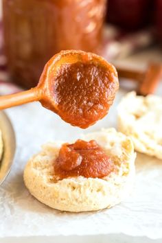 a spoon full of jam being held over biscuits