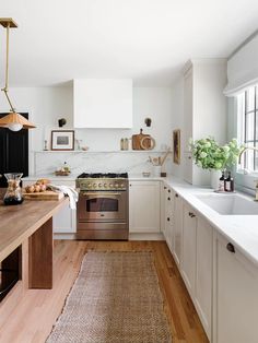 an open kitchen with white cabinets and wood flooring, along with a rug on the floor