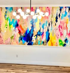 a large colorful painting on the wall in an empty room