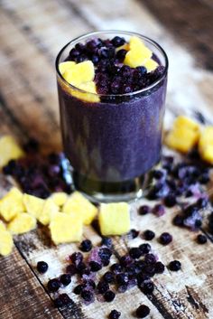 blueberry and pineapple smoothie in a glass with chopped fruit on the side