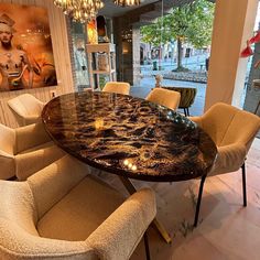 a dining table with chairs around it in front of a large painting on the wall