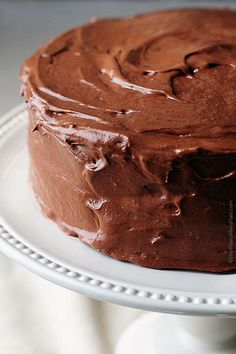 a chocolate frosted cake sitting on top of a white plate