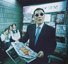 a man in a suit and tie holding up a newspaper while people watch from the subway