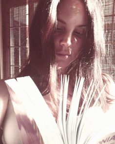 a woman is reading a book in the sun with her eyes closed and she has long dark hair