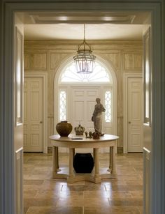 an entry way with a table and vases on the floor in front of it