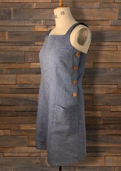 a mannequin wearing a gray dress with buttons on the back and neckline