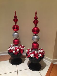 two red and silver vases filled with flowers on top of a white tile floor