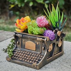 an old typewriter planter with flowers and succulents in it sitting on a table