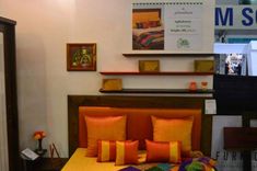 a bed with orange and yellow pillows in a room next to a sign that says m square