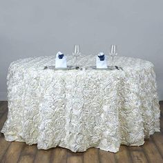 two wine glasses sitting on top of a table covered in white rosette cloths