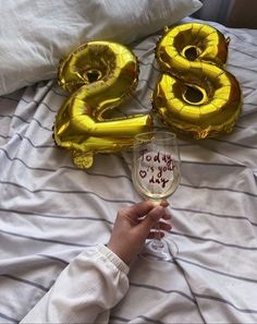 a person holding a wine glass with the number twenty eight on it and balloons in the shape of numbers