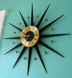 a gold and black clock mounted to the side of a wall with spikes on it