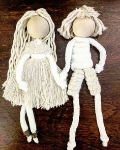 two dolls made out of yarn sitting on top of a wooden table next to each other