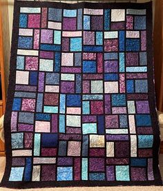 a purple and blue quilt sitting on top of a wooden floor