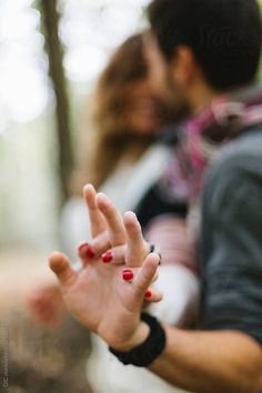 a man and woman are kissing in the woods with their hands extended out to kiss