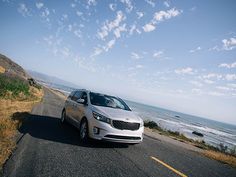 the car is driving down the road by the ocean