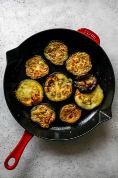 an iron skillet filled with cooked food on top of a white counter next to a red spatula