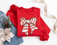 Christmas Coquette Bow Sweatshirt, Santa Claus Bow Shirt, Red Bow Christmas T-Shirt, Holiday Xmas Apparel, Christmas Women Sweater Hello! Thank you for supporting small businesses. My main priority here is the satisfaction of my customers. High quality and super soft, comfortable shirt. Made with special quality vinyl and pressed with a first class heat press. 𝗛𝗢𝗪 𝗧𝗢 𝗢𝗥𝗗𝗘𝗥 𝟏. Please, Check and Review all Listing Photos. 𝟐. Select Your Size and Color from drop down menus. 𝟑. Choose Y Red Long Sleeve Christmas T-shirt, Red Holiday Sweatshirt For Winter, Red Holiday Crew Neck T-shirt, Holiday Red Crew Neck T-shirt, Red Festive Holiday Top, Red Crew Neck Holiday T-shirt, Red Crew Neck T-shirt For Holidays, Red Holiday Tops For Festive Occasion, Red Cotton Top For Gift