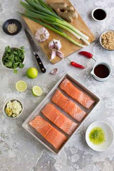 raw salmon fillets on a baking sheet, surrounded by ingredients to make the dish