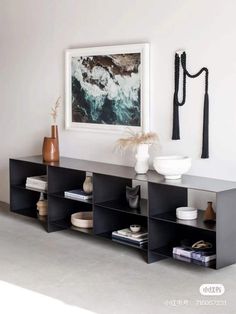 a shelf with vases and other items on it in front of a white wall