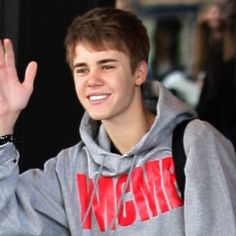 a young man waves to the crowd while wearing a sweatshirt