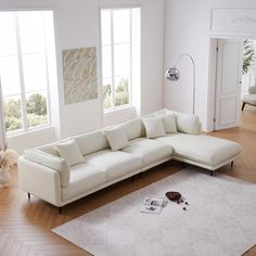 a living room with white furniture and hardwood floors, including a large sectional sofa in the middle