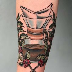 a tattoo on the leg of a person with a cup of coffee and two crossed swords