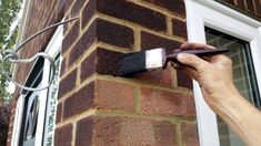 a man is painting the outside of a brick building with a paintbrush and brush